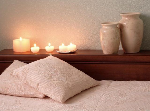 Bougies à côté d'un lit avec des oreillers.